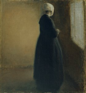 An old woman standing by a window by Vilhelm Hammershøi